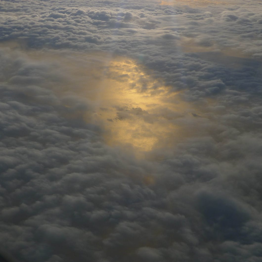 aerial photo from a plane, sunlight, clouds over the sea